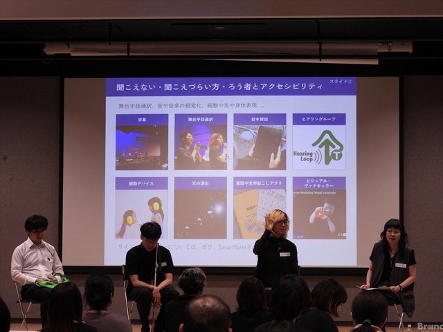 4人の登壇者が並んで座るパネルディスカッションの様子。背後のスクリーンには『聞こえない・聞こえづらい方・ろう者とアクセシビリティ』に関するスライドが投影され、手前には観客の姿が見える